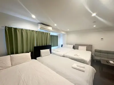 a room with three beds and a couch in it at \u30a2\u30f3\u30c9\u30b9\u30c6\u30a4\u3059\u3082\u3046\u30db\u30c6\u30eb402 in Tokyo