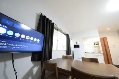 a room with a tv and a table with chairs at \u548c\u306e\u6953cottage\u7b2c\u4e8c202 \u65b0\u5bbf\u6b4c\u821e\u4f0e\u753a\u8fd1\u96a3 in Tokyo