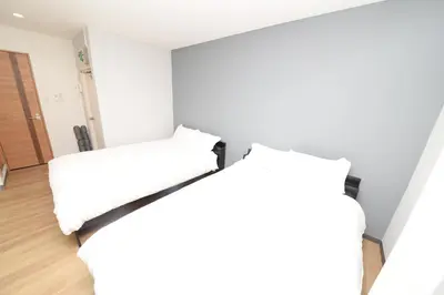 two beds in a room with white walls at \u548c\u306e\u6953cottage\u7b2c\u4e8c202 \u65b0\u5bbf\u6b4c\u821e\u4f0e\u753a\u8fd1\u96a3 in Tokyo