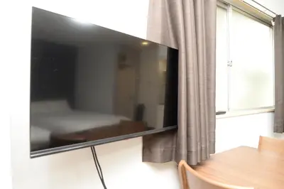 a flat screen tv hanging on a wall next to a window at \u548c\u306e\u6953cottage\u7b2c\u4e8c202 \u65b0\u5bbf\u6b4c\u821e\u4f0e\u753a\u8fd1\u96a3 in Tokyo