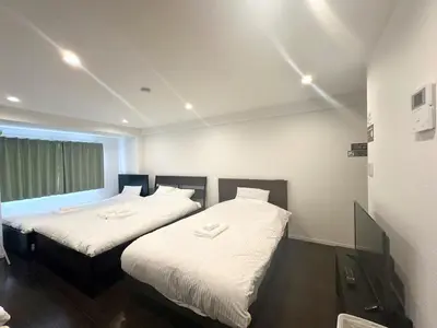 two beds with white sheets in a room at \u30a2\u30f3\u30c9\u30b9\u30c6\u30a4\u3059\u3082\u3046\u30db\u30c6\u30eb403 in Tokyo