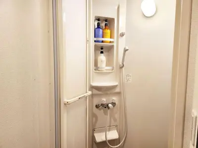 a bathroom with a shower with bottles on the door at \u30a2\u30f3\u30c9\u30b9\u30c6\u30a4\u3059\u3082\u3046\u30db\u30c6\u30eb403 in Tokyo