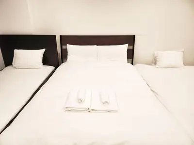 two beds with white sheets and a pair of slippers at \u30a2\u30f3\u30c9\u30b9\u30c6\u30a4\u3059\u3082\u3046\u30db\u30c6\u30eb403 in Tokyo