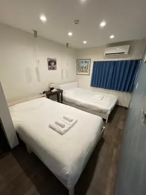 a hospital room with two beds with white sheets at \u30a2\u30f3\u30c9\u30b9\u30c6\u30a4\u30ce\u30dc\u30c3\u30c1\u30db\u30c6\u30eb101 in Tokyo
