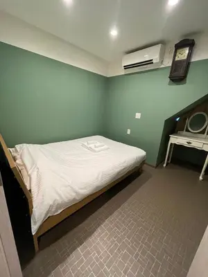 a bed in a room with a green wall at \u30a2\u30f3\u30c9\u30b9\u30c6\u30a4\u30ce\u30dc\u30c3\u30c1\u30db\u30c6\u30eb101 in Tokyo