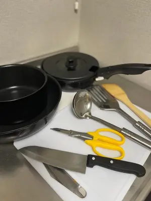 a table with utensils and a frying pan on a stove at \u30a2\u30f3\u30c9\u30b9\u30c6\u30a4\u30ce\u30dc\u30c3\u30c1\u30db\u30c6\u30eb201 in Tokyo
