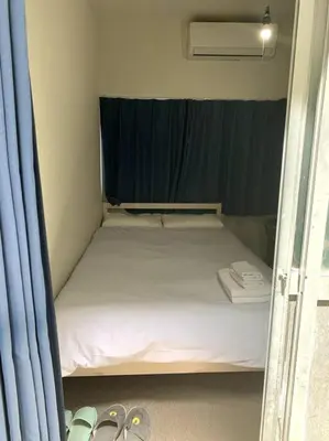 a small bed in a small room with two pairs of shoes at \u30a2\u30f3\u30c9\u30b9\u30c6\u30a4\u30ce\u30dc\u30c3\u30c1\u30db\u30c6\u30ebn3 in Tokyo