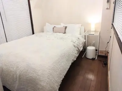 a bedroom with a bed with white sheets and a lamp at Casa Tokyo -Arakicho- in Tokyo
