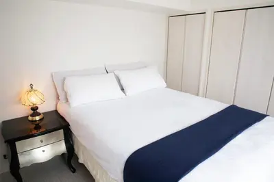 a small bedroom with a white bed and a night stand at \u862d\u5712 Village Gotanda \u5c4b\u4e0a\u30ac\u30fc\u30c7\u30f3\u30c6\u30e9\u30b9\u4ed8\u304d in Tokyo