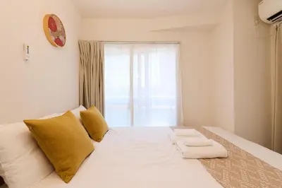 a white bed with yellow pillows and a window at Home Story in Tokyo Ueno&Uguisudani-小島ビル&東京屋語 in Tokyo
