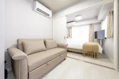 a white living room with a couch and a bed at Provence Hotel in Tokyo