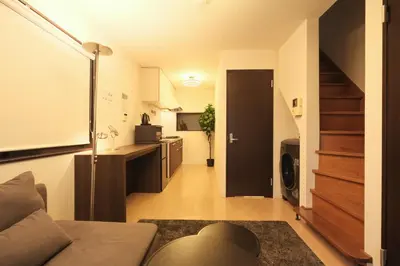 a living room with a couch and a kitchen at Urban House Nakano in Tokyo