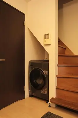 a washing machine in a hallway next to a staircase at Urban House Nakano in Tokyo