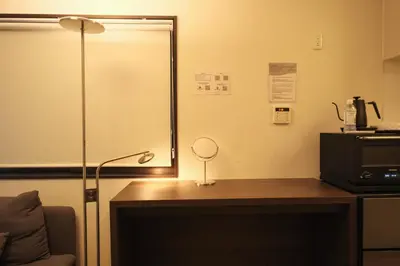 a room with a desk with a lamp and a microwave at Urban House Nakano in Tokyo