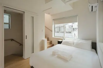 a bedroom with a white bed and a window at Urban House Hatagaya in Tokyo