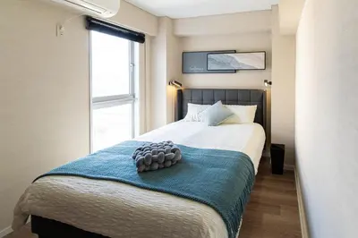 a bedroom with a bed with a blue blanket and a window at Z7\u5168\u65b0\u88c5\u4fee\u5957\u623f3\u5ba42\u5385 \u65b0\u5bbf2\u7ad94\u5206\u949f,Max 8p-spacious,3rooms Near Shinjuku in Tokyo