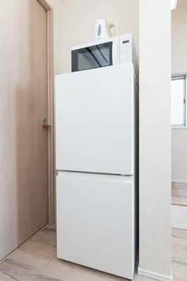 a white refrigerator with a microwave on top of it at \u30d9\u30eb\u9418 in Tokyo