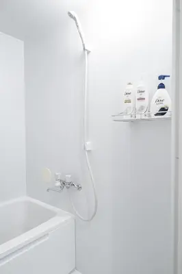 a white bathroom with a shower and a sink at \u532f\u5bb6\u672c\u753a\u30d3\u30eb in Tokyo