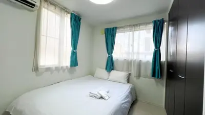 a small bedroom with a white bed with blue curtains at JING HOUSE Shintakasago - Vacation STAY 17117 in Tokyo