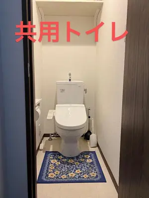 a bathroom with a white toilet with a blue rug at \u6c11\u6ccaTOKYO one \u30b7\u30a7\u30a2\u30cf\u30a6\u30b9 in Tokyo