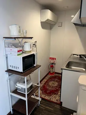 a small kitchen with a microwave on a shelf at \u6c11\u6ccaTOKYO one \u30b7\u30a7\u30a2\u30cf\u30a6\u30b9 in Tokyo