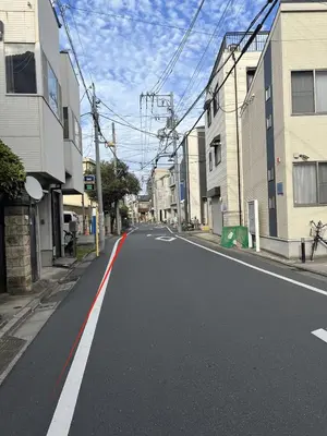 an empty street in a city with buildings at \u6c11\u6ccaTOKYO one \u30b7\u30a7\u30a2\u30cf\u30a6\u30b9 in Tokyo