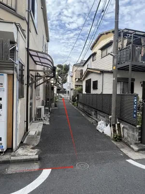 an empty street with a red line on the road at \u6c11\u6ccaTOKYO one \u30b7\u30a7\u30a2\u30cf\u30a6\u30b9 in Tokyo