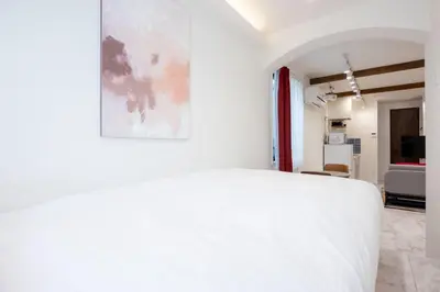 a bedroom with a white bed with a painting on the wall at Recorrido Yoyogi in Tokyo