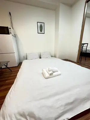 a white bed with two towels on top of it at SOLASIA residence \u5317\u4e0a\u91ce601 in Tokyo