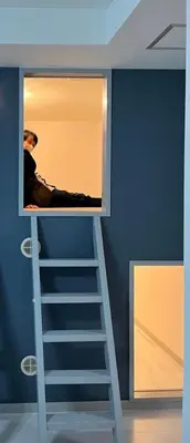 a man sitting on a ladder in a room at Space Noa201 in Tokyo