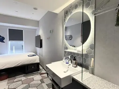a bathroom with a bed and a sink and a mirror at lyf Shibuya Tokyo in Tokyo