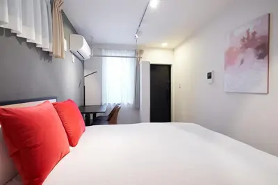 a bedroom with a bed with red pillows and a desk at Ruygo\u65b0\u5bbf\u897f\u843d\u5408 in Tokyo