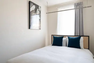 a bedroom with a bed with blue pillows and a window at Ruygo\u65b0\u5bbf\u897f\u843d\u5408 in Tokyo
