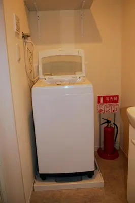 a small white refrigerator in a corner of a room at The FLAT 103 in Tokyo