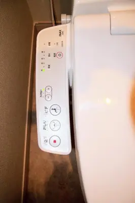 a white remote control sitting next to a wall at The FLAT 103 in Tokyo