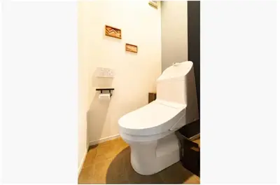 a white toilet in a bathroom with two pictures on the wall at 64, Shiomi , Second floor of the apartment, \u6f6e\u898b2F in Tokyo