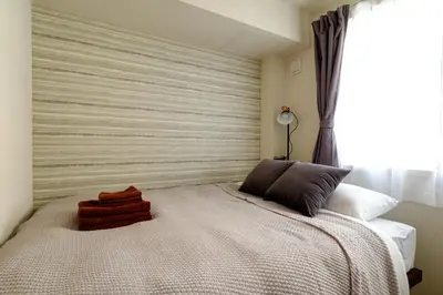 a bedroom with a bed with a large window at Asakusa Landing - \u96f7\u9580\u3084\u6d45\u8349\u5bfa\u307e\u3067\u5f92\u6b69\u570f\u5185 - \u7121\u6599Wi-Fi\u3084\u30d7\u30ed\u30b8\u30a7\u30af\u30bf\u30fc\u5b8c\u5099 in Tokyo