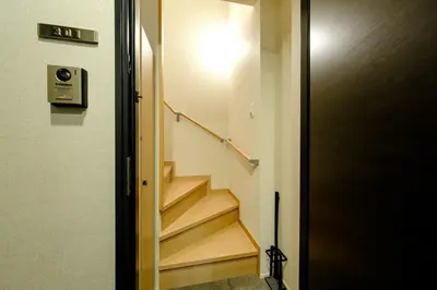 a hallway with stairs leading up to a door at Asakusa Landing - \u96f7\u9580\u3084\u6d45\u8349\u5bfa\u307e\u3067\u5f92\u6b69\u570f\u5185 - \u7121\u6599Wi-Fi\u3084\u30d7\u30ed\u30b8\u30a7\u30af\u30bf\u30fc\u5b8c\u5099 in Tokyo