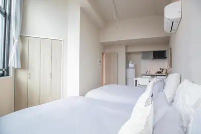 a white bedroom with two beds and a kitchen at The best choice for accommodation in Yoyogi SoYk in Tokyo