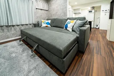 a gray couch in a living room with a kitchen at 93, Yotsugi Seven, Entire house for rent, \u56db\u3064\u6728\u30bb\u30d6\u30f3 in Tokyo