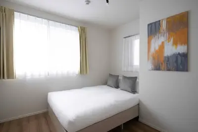 a bedroom with a white bed and a painting on the wall at \u7be0\u30ac\u30fc\u30c7\u30f3\u30ec\u30b8\u30c7\u30f3\u30b9 in Tokyo