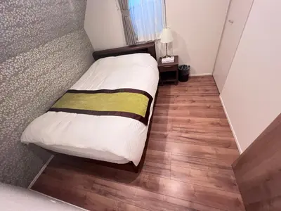 a small bed in a room with a wooden floor at new open shinjuku house SJ0430 in Tokyo