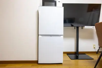 a white refrigerator sitting next to a desk at \u9326\u7cf8\u753a\u30b9\u30ab\u30a4\u30a8\u30a4\u30c8 in Tokyo