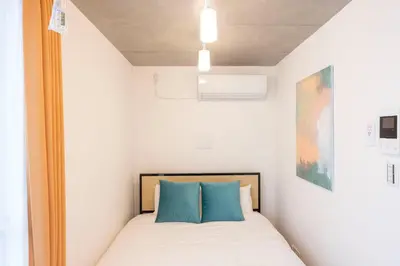 a small bedroom with a bed with blue pillows at Arucia\u4e09\u8ed2\u8336\u5c4b in Tokyo