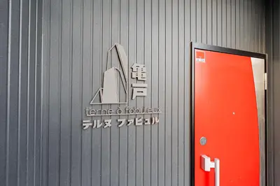 a sign on the side of a building with a red door at テルヌファビュル亀戸 - Tokyo Urban APT in a Japanese Local Shopping Street, with Direct Access to Shinjuku & Akihabara in Tokyo