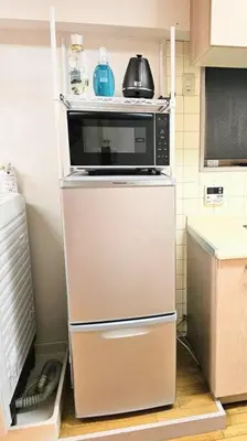 a microwave sitting on top of a refrigerator in a kitchen at \u834f\u539f\u4e2d\u5ef6\u99c5\u304b\u30893\u5206,\u5e83\u3005LDK,\u8cb8\u5207,\u54c1\u5ddd\u99c5\u307e\u306720\u5206,comfortable in Tokyo