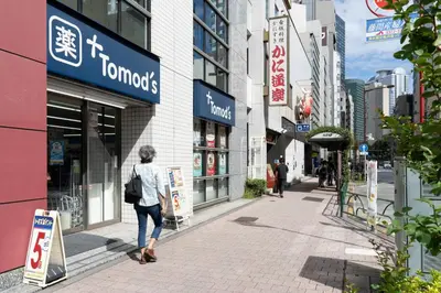 a woman walking down a sidewalk in a city at Link COURT\u897f\u65b0\u5bbf in Tokyo