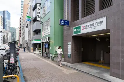 a woman walking out of a building at Link COURT\u897f\u65b0\u5bbf in Tokyo