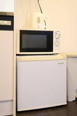 a microwave sitting on top of a refrigerator at \u30a2\u30f3\u30c9\u30b9\u30c6\u30a4\u3059\u3082\u3046\u30db\u30c6\u30eb401 in Tokyo