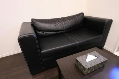 a black leather couch in a living room with a coffee table at \u30a2\u30f3\u30c9\u30b9\u30c6\u30a4\u3059\u3082\u3046\u30db\u30c6\u30eb401 in Tokyo